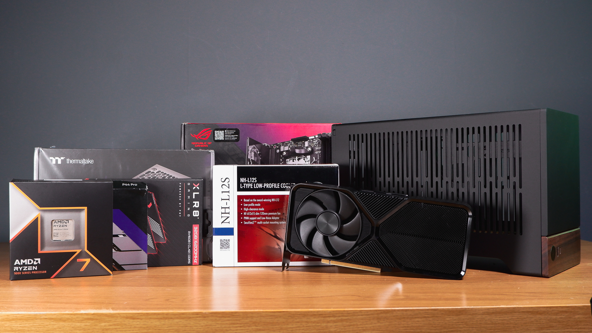 A compact gaming PC on a desk with various parts on show.