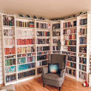 A colorful set of bookshelves in a corner with a reading chair next to it