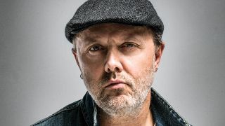 A portrait of Lars Ulrich on a grey background, looking at the camera