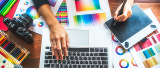 A designer using a laptop and tablet, surrounded by color palettes