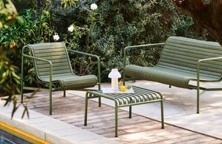 A green metal garden bench seat and chair in a contemporary garden
