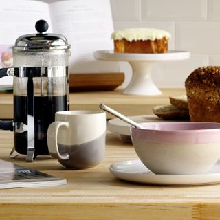 A breakfast spread with a coffee French press, mugs and bowls