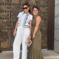 Princess eugenie wearing a green maxi dress standing with Ayda Field Williams in front of a door 