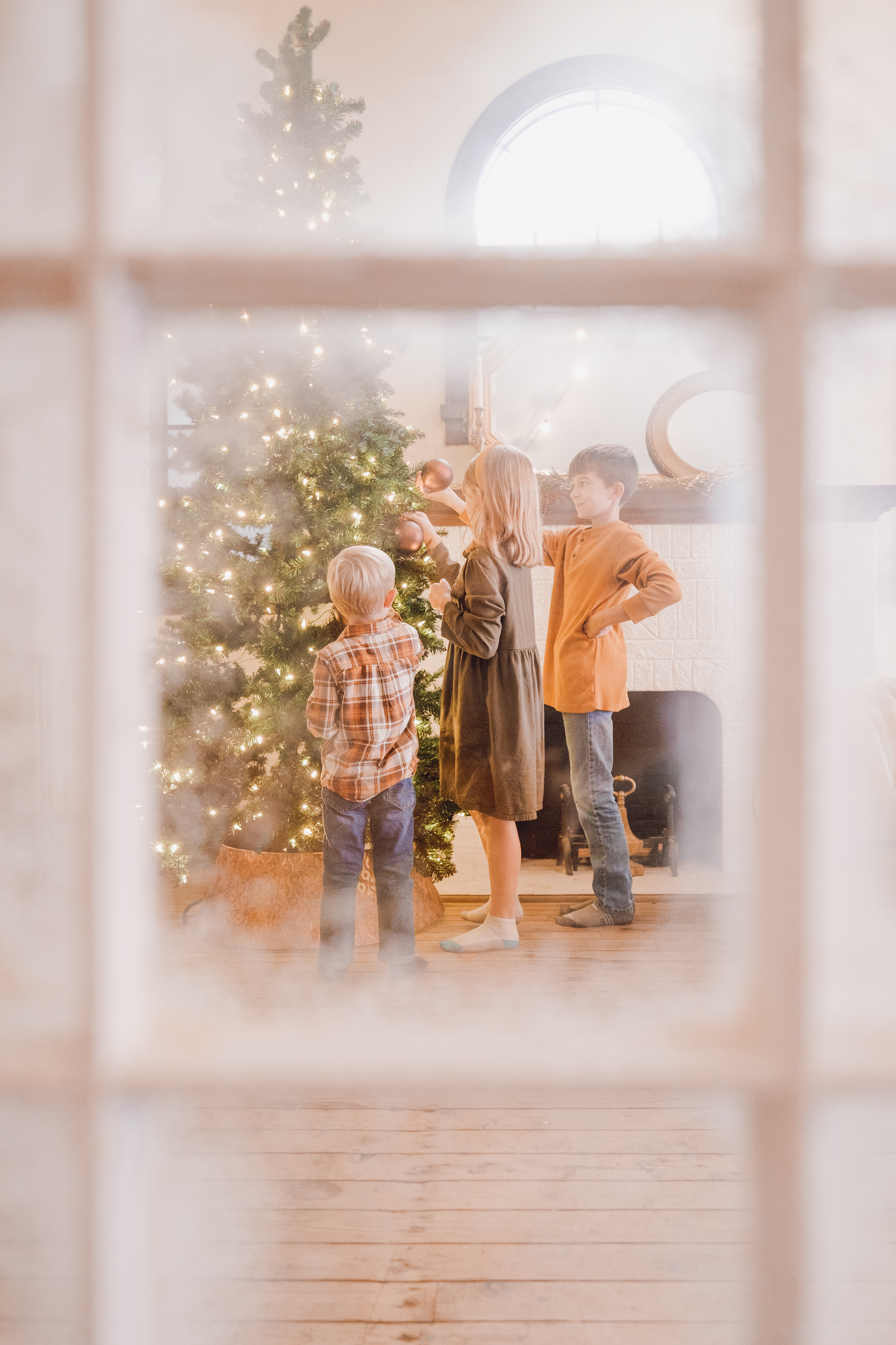 A snowy window frames a cozy Christmas scene