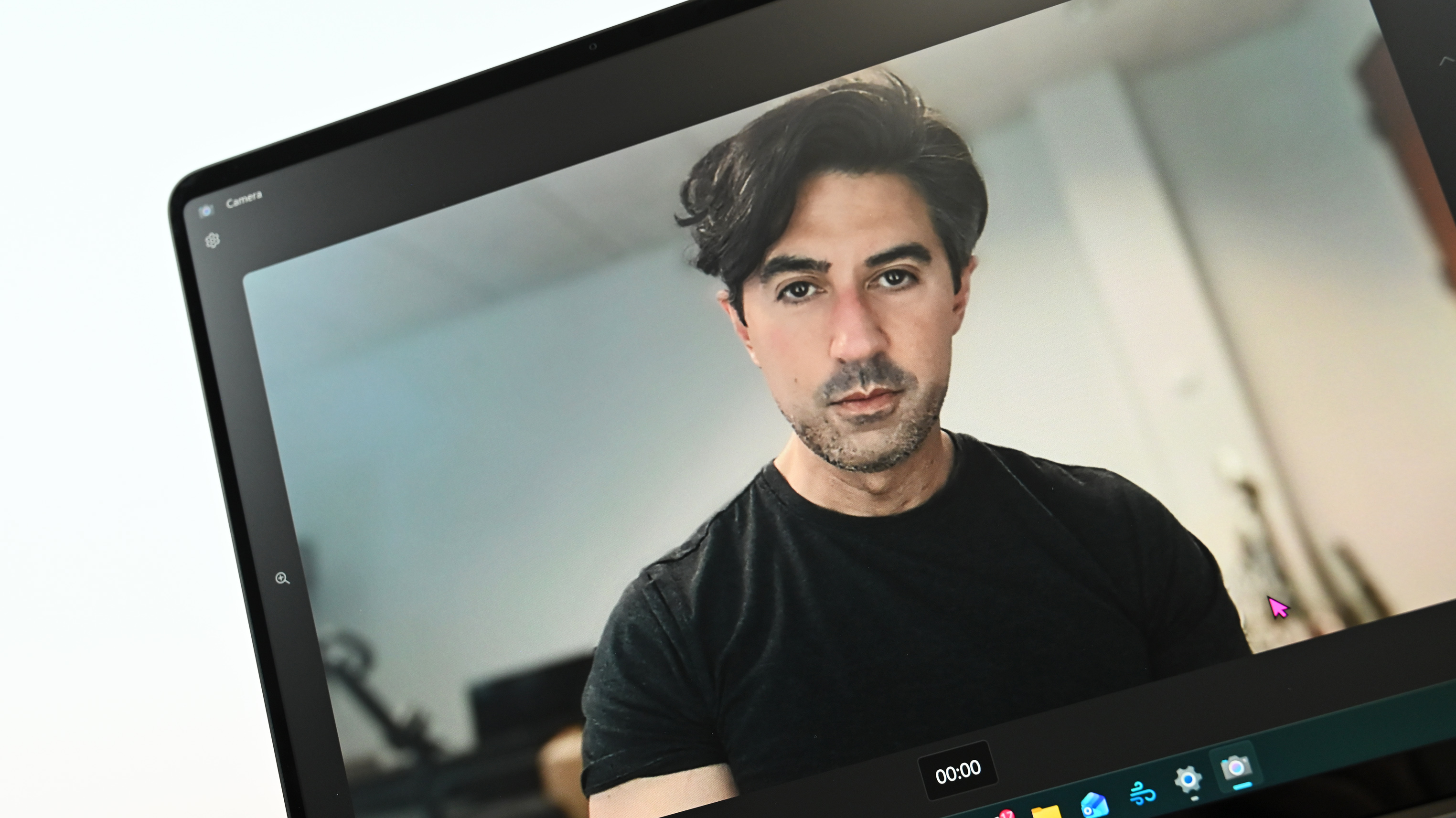 Daniel Rubino, with dark hair and a serious expression, is seen on Surface Laptop for Business 8th Edition's screen during a video call. He's wearing a black t-shirt in a well-lit room.