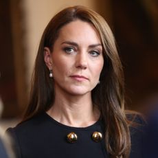 Kate Middleton has long brunette hair and wears a black outfit