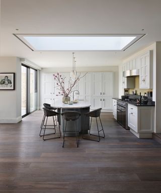 barely there gray kitchen units, dark wood floor, gray kitchen island, black stool