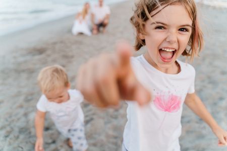 Cheerful happy children brother and sister play on the beach 