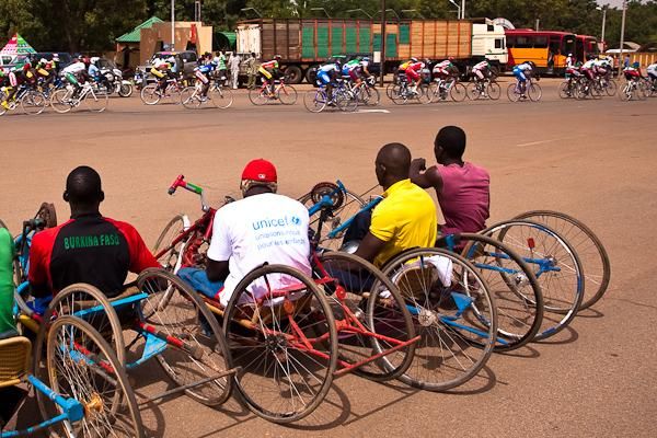 Handcycle racers watch the Tour du Faso peloton after competing in a demonstration race for the crowds of Ouagadougou.