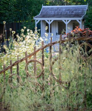An example of cottage garden ideas with a meadow and a rustic fence