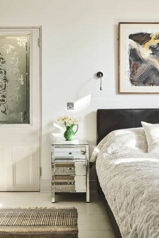 White bedroom with black headboard and mirrored side table