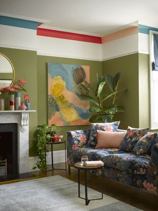 olive Green painting living room, with rug, navy blue floral sofa and colour bursts on the ceiling.