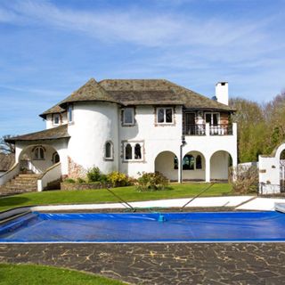 white villa with brown roof green lawn swimming pool and plants
