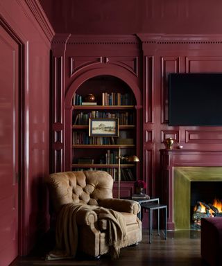 living room with gloss raspberry red walls and ceiling, tan vintage armchair and built-in bookshelf