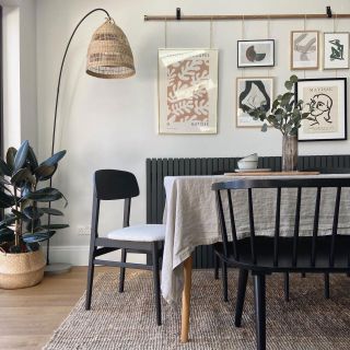 Dining area with table cloth on table, black bench seat and gallery wall hanging from a wooden pole