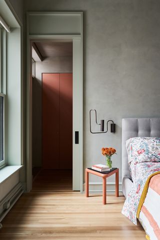 A bedroom with sage green walls and gray bed