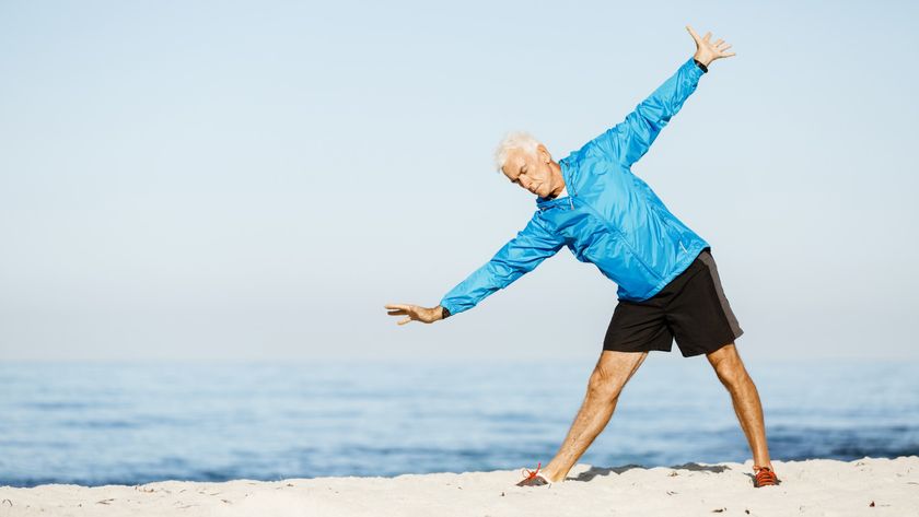 Older active male performing a yoga pose on the beach
