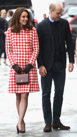 Kate Middleton in a red houndstooth coat, with Prince William