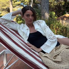 Influencer @maryljean wears a crochet cardigan over a black swimsuit with a crochet handbag.