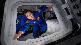 nicole mann astronaut stretching out hands at the entrance of a spacecraft