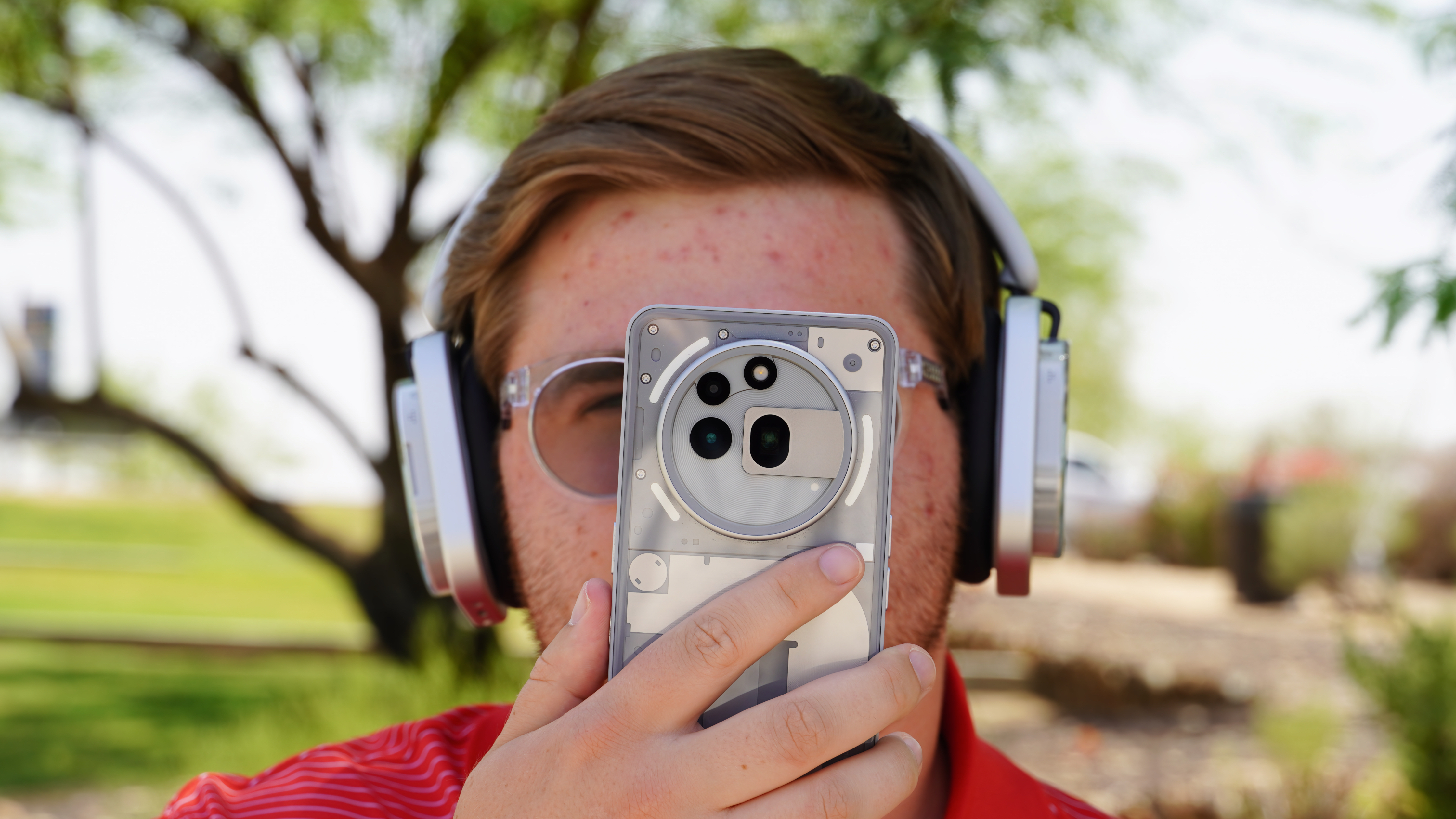 Wearing the Nothing Headphone 1 while holding up the Nothing Phone 3a Pro.
