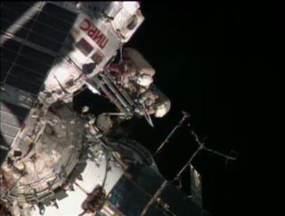 Russian cosmonauts Oleg Kotov and Sergey Ryazanskiy prepare to pass the Olympic torch in space during a spacewalk outside the International Space Station on Nov. 9, 2013. Kotov is holding the torch.