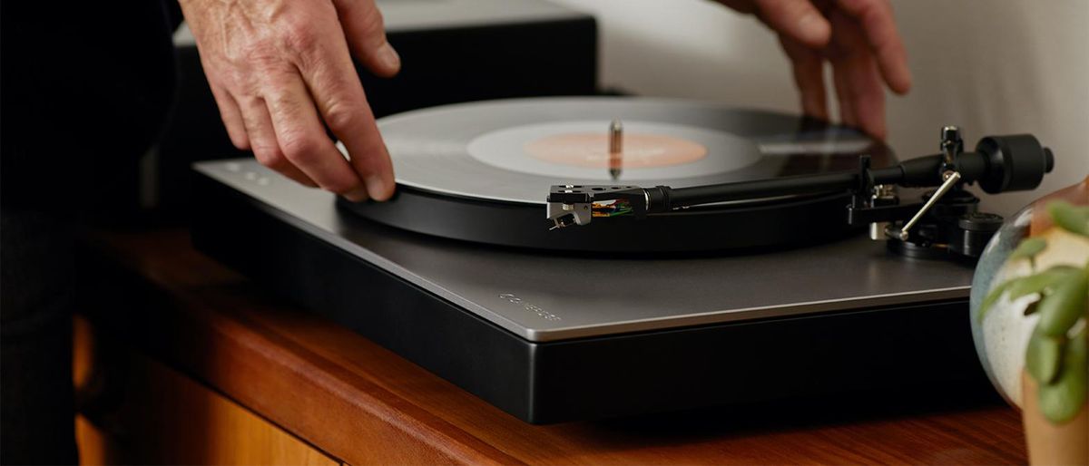 Cambridge Audio Alva TT V2 on sideboard, with man placing a record on the turntable