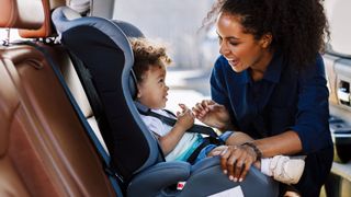 Image shows a mother smiling at her infant in one of the best travel car seats.
