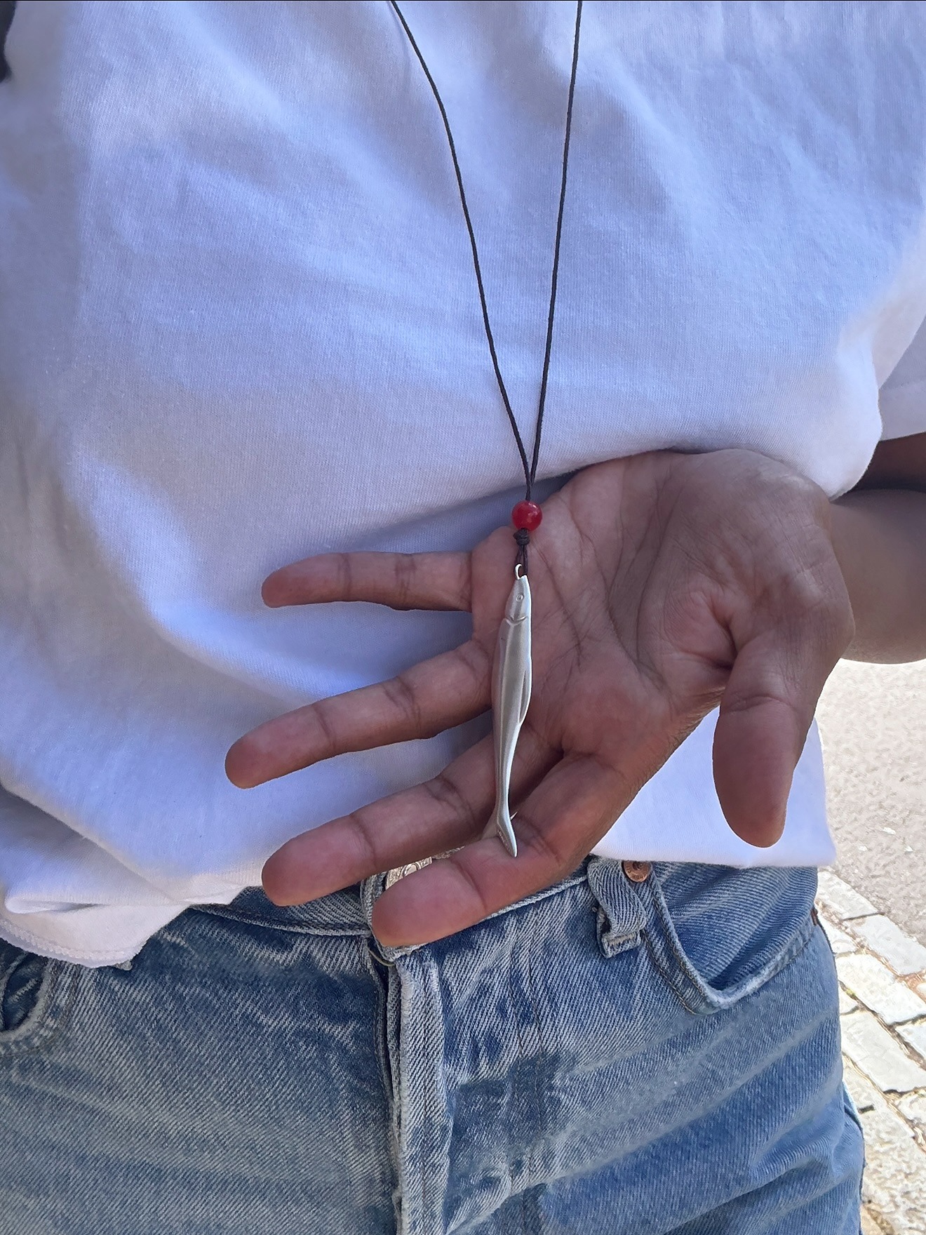 Influencer @monikh wears a fish necklace with a white t-shirt and jeans.