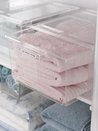 Towels and linens in labelled clear drawers on shelves