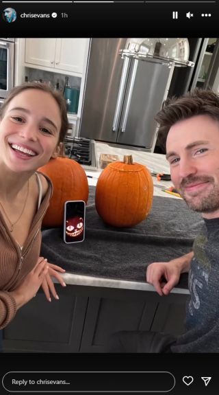Alba Baptista and Chris Evans posing for a selfie while carving pumpkins