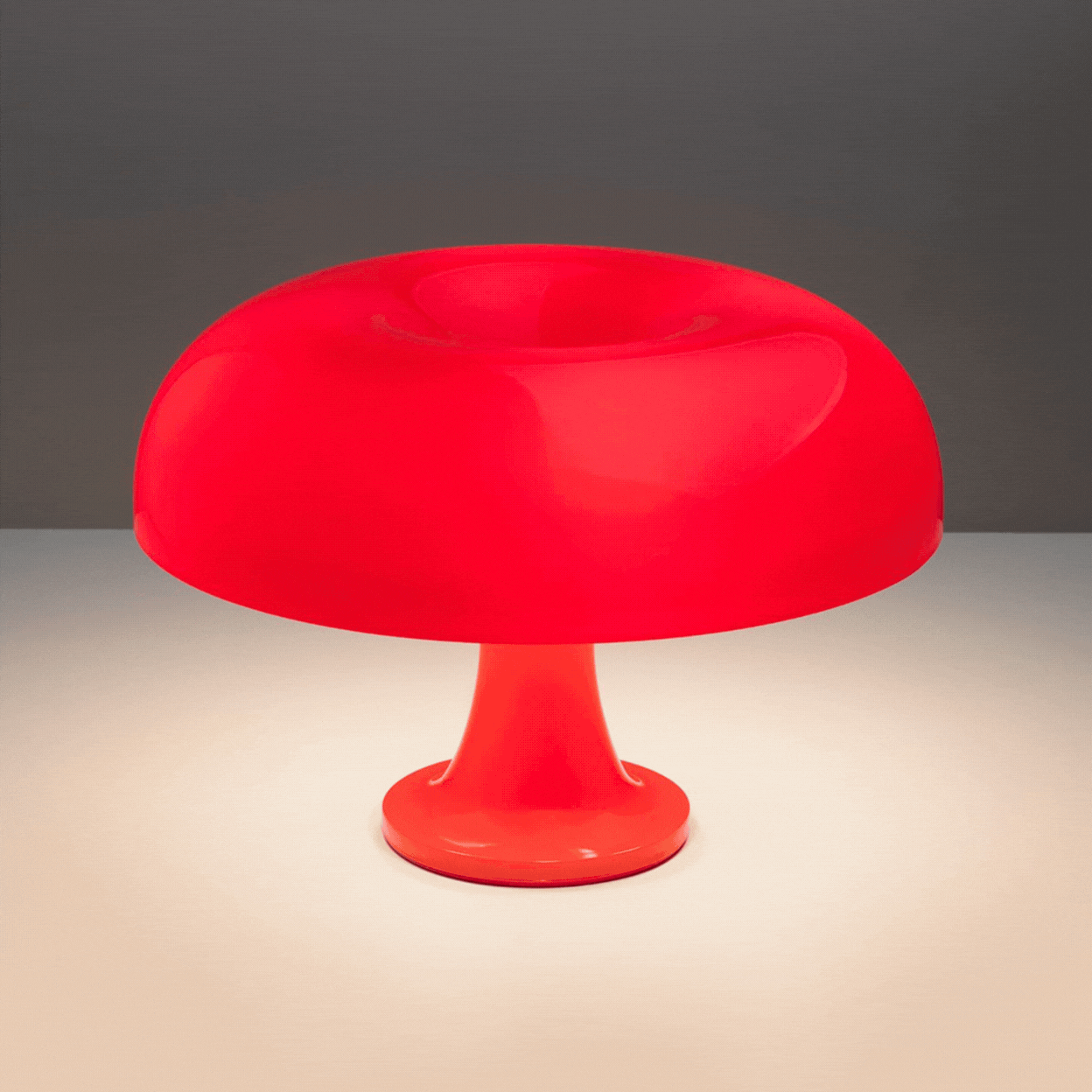 Artemide Nessino Table Lamp, a mushroom-shaped, red light, is captured in a rotating gif that shows it switched on, oozing with warm light, and off against a grey background.