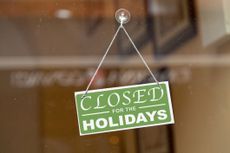 Green sign hanging at the glass door of a shop with written in it "Closed for the holidays".