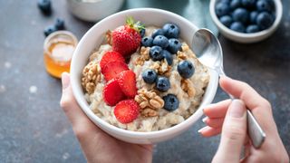 A collection of berries scattered across porridge with nuts, the best fruit for weight loss