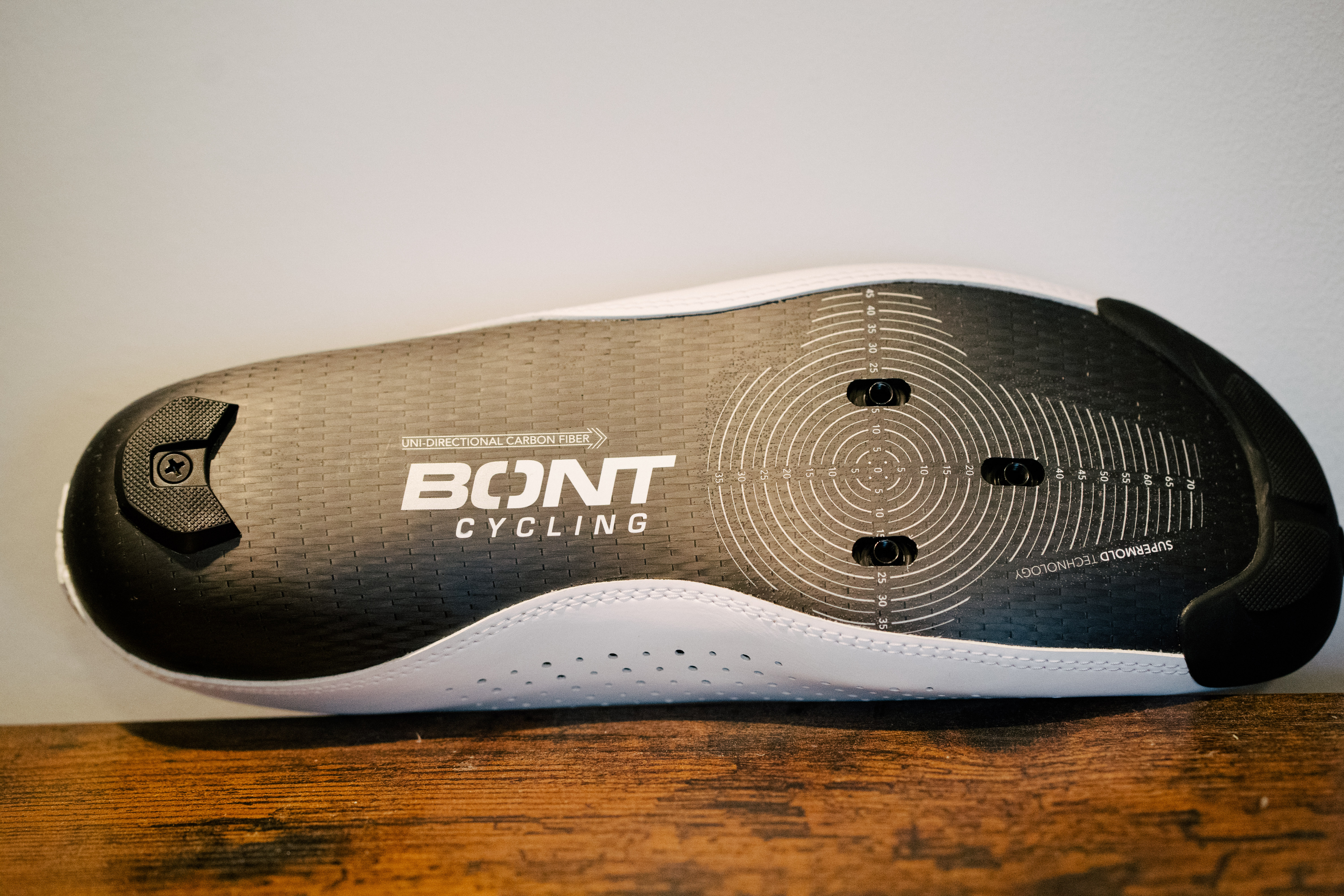 A lace up set of bike shoes on a wooden shelf