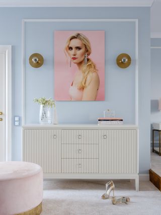 A bedroom with powder blue walls and light pink painting