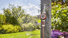 Gardena Water Timer in use to water a garden, with grass and bushes shown