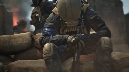 Wardogs solider sitting with hands clasped around rifle
