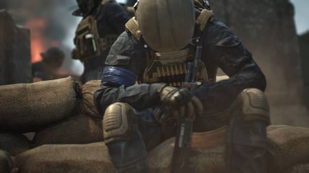 Wardogs solider sitting with hands clasped around rifle
