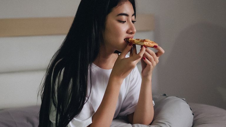 foods to help you sleep - woman eating pizza in bed