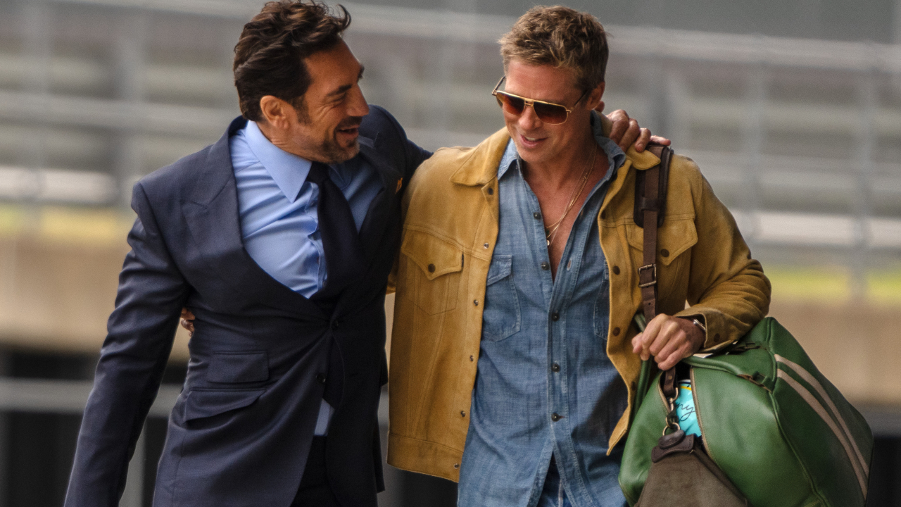 A smiling Javier Bardem walks the track with his arm around Brad Pitt in F1.