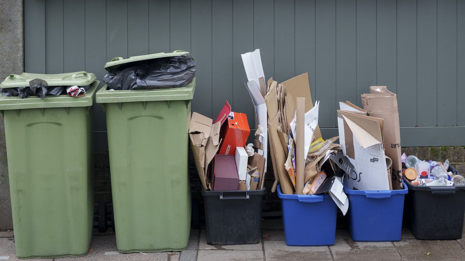 Recycling bins containing plastic and cardboard packaging waste await collection by a Richmond upon Thames council waste collection in Barnes