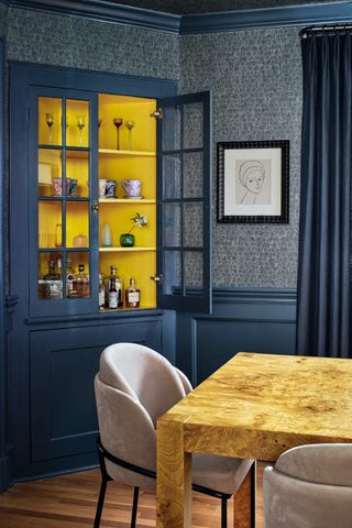 A photo of a blue room with built-in cabinet painted bright yellow inside