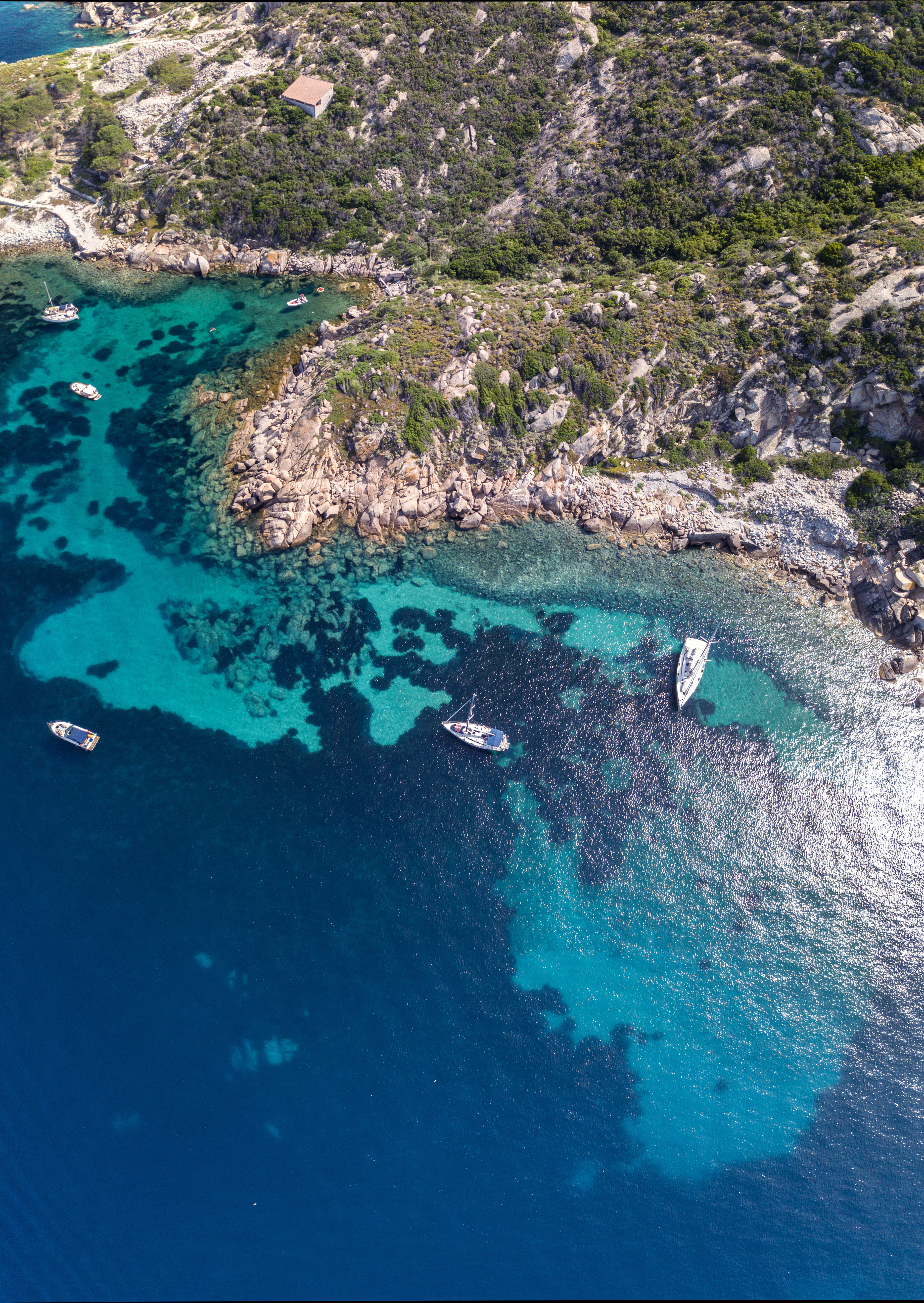 Aerial shot if Giglio island coastline with five boats moored
