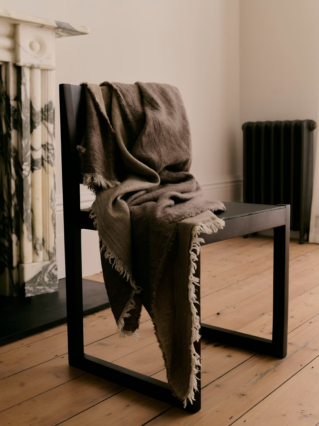 A green merino wool throw from Rise &amp;amp; Fall draped across a wood chair