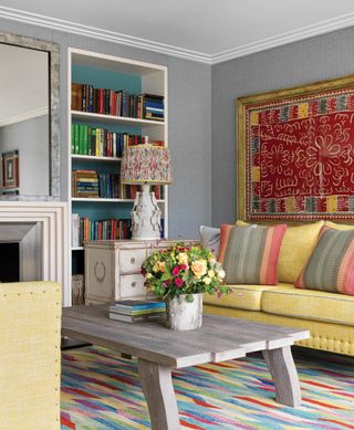 Grey paint and yellow sofa surrounding a multi-colored rug