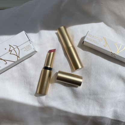 the Lisa Eldridge Baume Embrace Melting Lip Colour balms in their packaging on a linen sheet