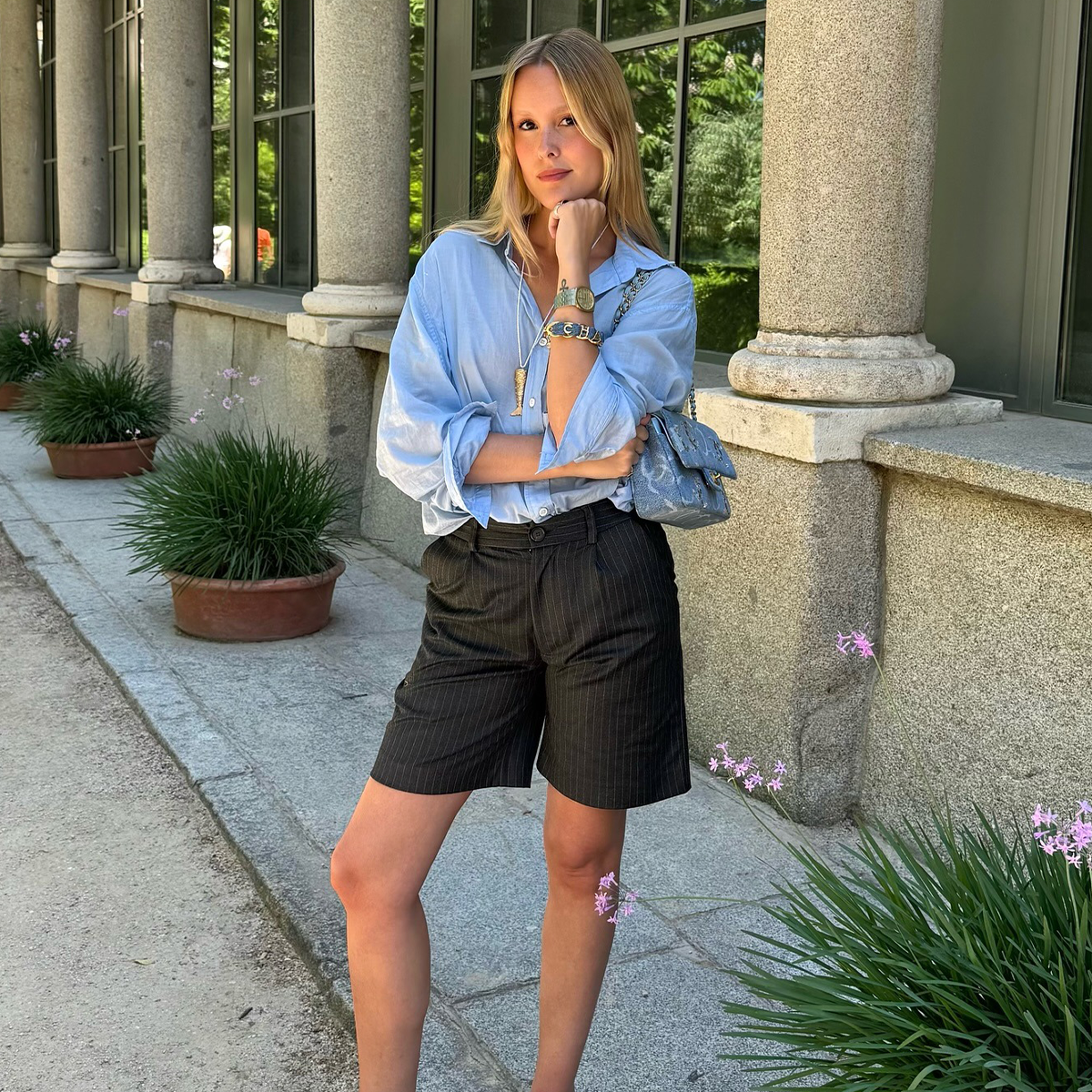 Woman wearing blue button-down shirt, black shorts, and colorful jewelry in Madrid.