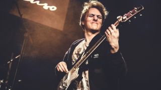 Matteo Mancuso plays his guitar on stage with a fretwrap on the headstock