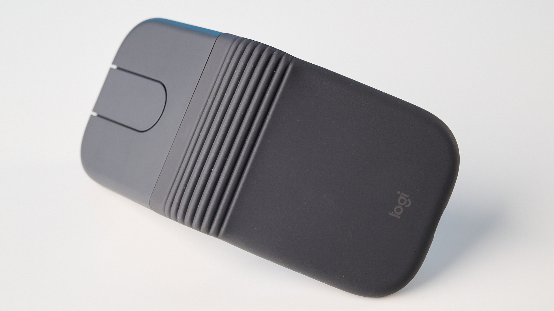 Logitech Mobi Fold mouse in graphite photographed in front of a blue background
